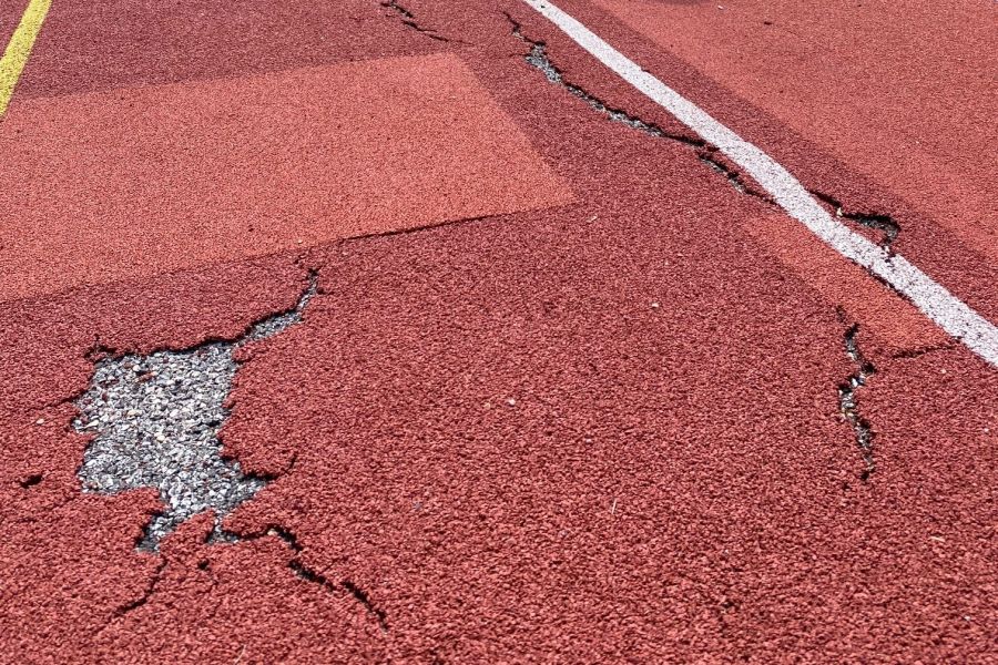 Sportplatzbelag mit Rissen und Löchern