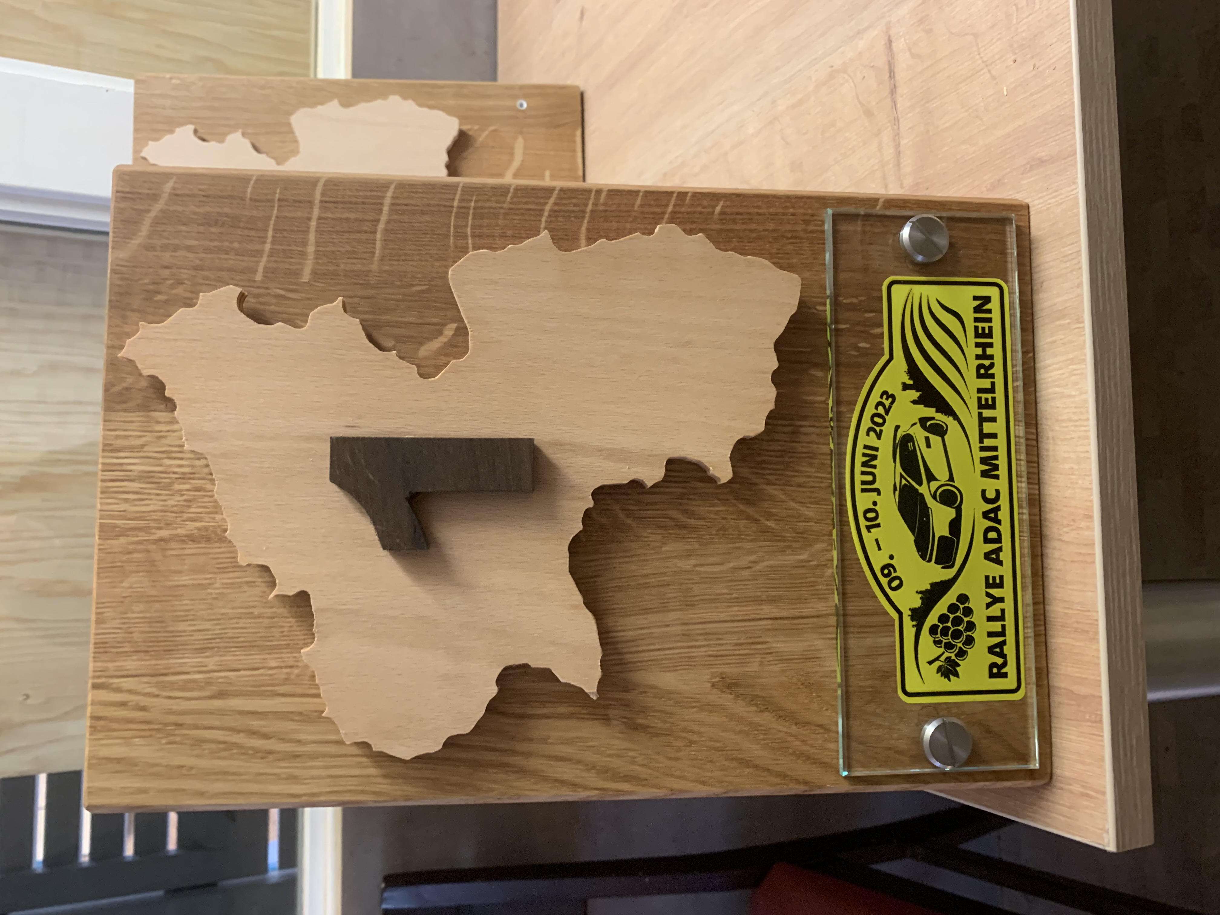 Hölzerne Trophäe der Rallye ADAC Mittelrhein 2023 mit einer Karte, der Zahl 1 und dem Datum 09.-10. Juni.