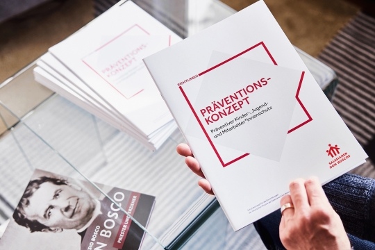 Das Pr&auml;ventionskonzept der Salesianer Don Boscos, im Hintegrund liegt ein Buch mit einem Bild Don Boscos.