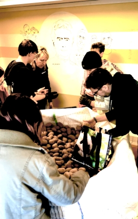 Mehrere Menschen stehen um einen großen weißen Sack mit Kartoffeln.