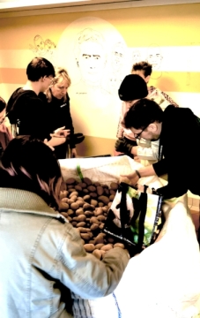 Mehrere Menschen stehen um einen großen weißen Sack mit Kartoffeln.