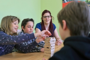 Erzieherin spielt fröhlich mit Kindern, die begeistert Bauklötze stapeln.JPG