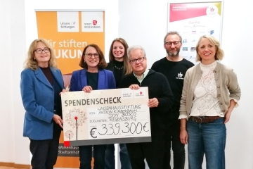 Vier Männer und zwei Frauen halten einen großen Spendenscheck in den Händen
