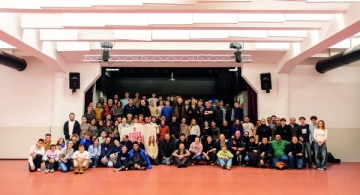 Eine Gruppe von Menschen steht treppenartig vor einer Bühne.