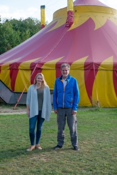 Lisa Kestel, Leiterin der Flex Fernschule Bayern, und Emil Hartmann, Gesamtleiter des Don Bosco Jugendwerks Bamberg, vor dem gelb-roten Zirkuszelt des Jugendwerks