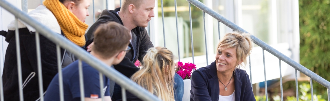 Eine Frau im Gespräch mit Jugendlichen