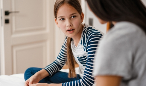 Mädchen unterhält sich mit Mutter auf Bett