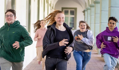Jugendliche rennen lachend durch die Arkaden im Kloster Benediktbeuern