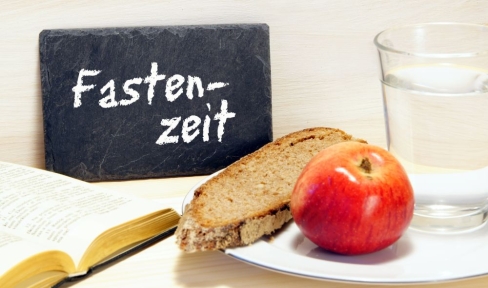 Brot, Apfel, Bibel, Wasser und Schild mit Aufschrift Fastenzeit