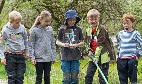 Kinder erforschen mit Käscher an Tümpel die Natur 