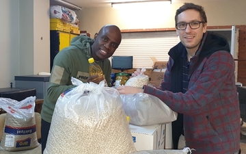 Pater Jacky Doyen und Pater Simon Härting packen Lebensmittel für bedürftige Familien ein. 