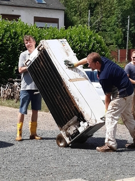 Zwei Mitarbeiter beseitigen den Schutt nach der Flut in Trier. Das Hochwasser stellte die Jugendhilfe vor große Herausforderungen. 