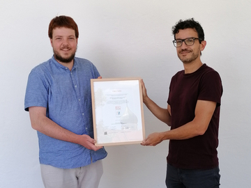 Niklas Gregull und Francesco Bagiolini zeigen die Urkunde für die Auszeichnung mit dem RAL-Gütezeichen